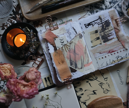 art table with artist collage journal with bits of collage paper on desk