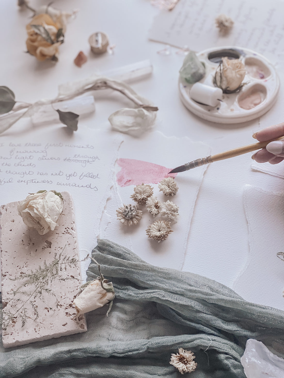 inspiring artist table with painted paper and artist hand holding a paintbrush. 