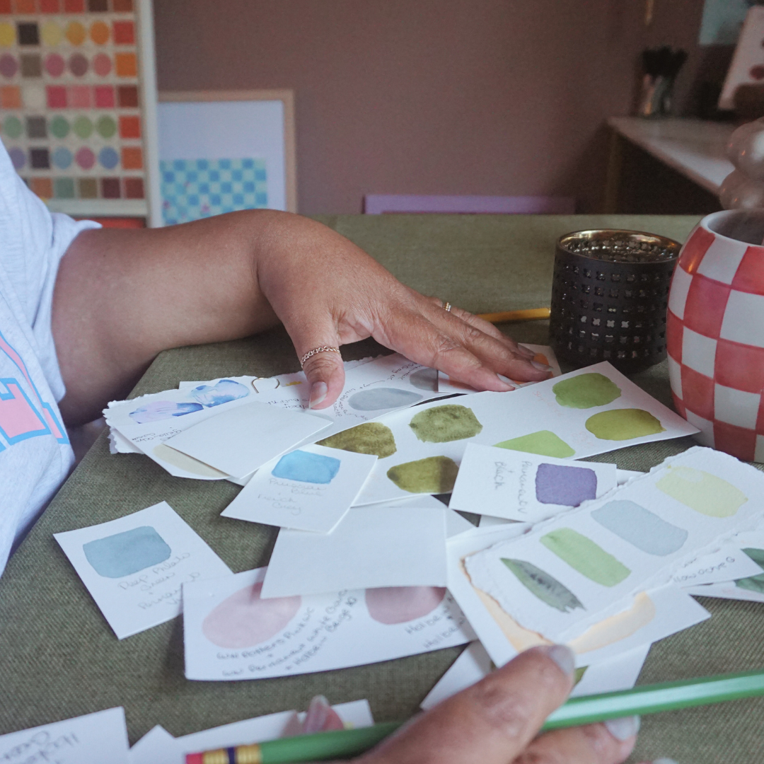 artist desk with color swatches, hands on desk, and pencil in hand, demonstrating color theory for painting and art,